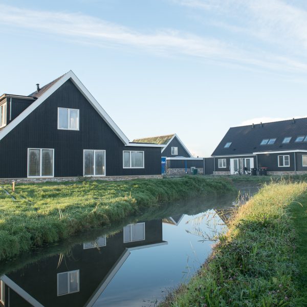 Foto van huizen met gras en sloot